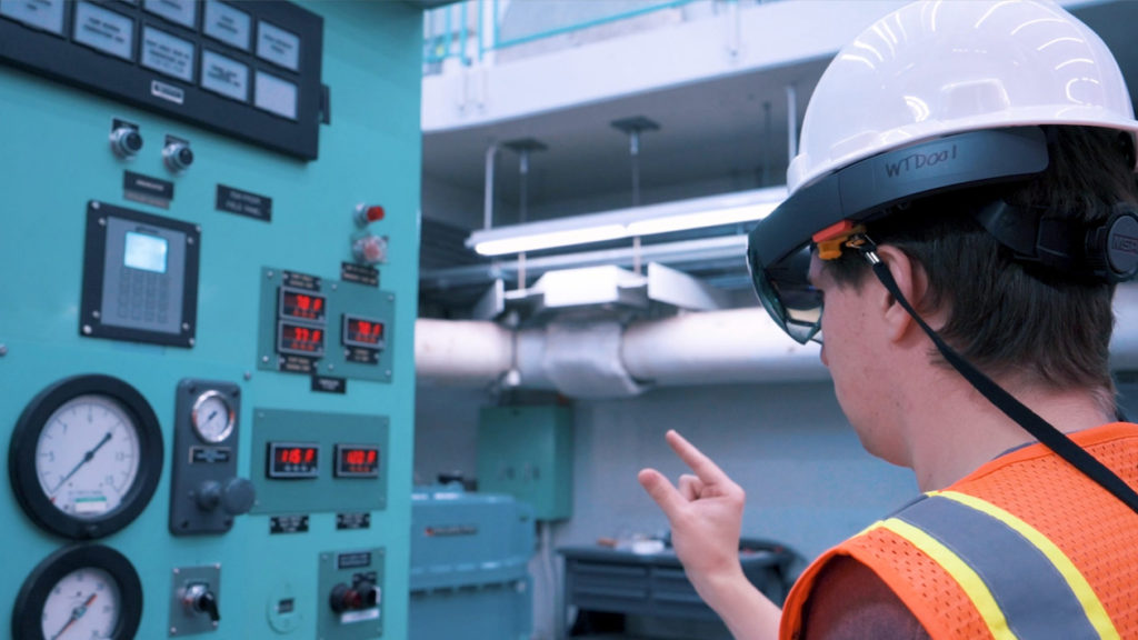 person in hard hat wearing ar headset looking at a machine