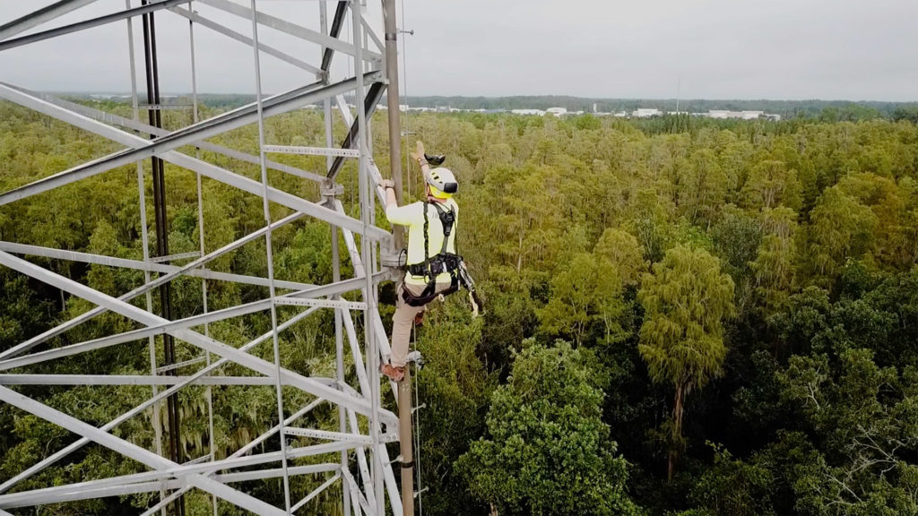 utility worker climbing a cell tower while wearing ar headset