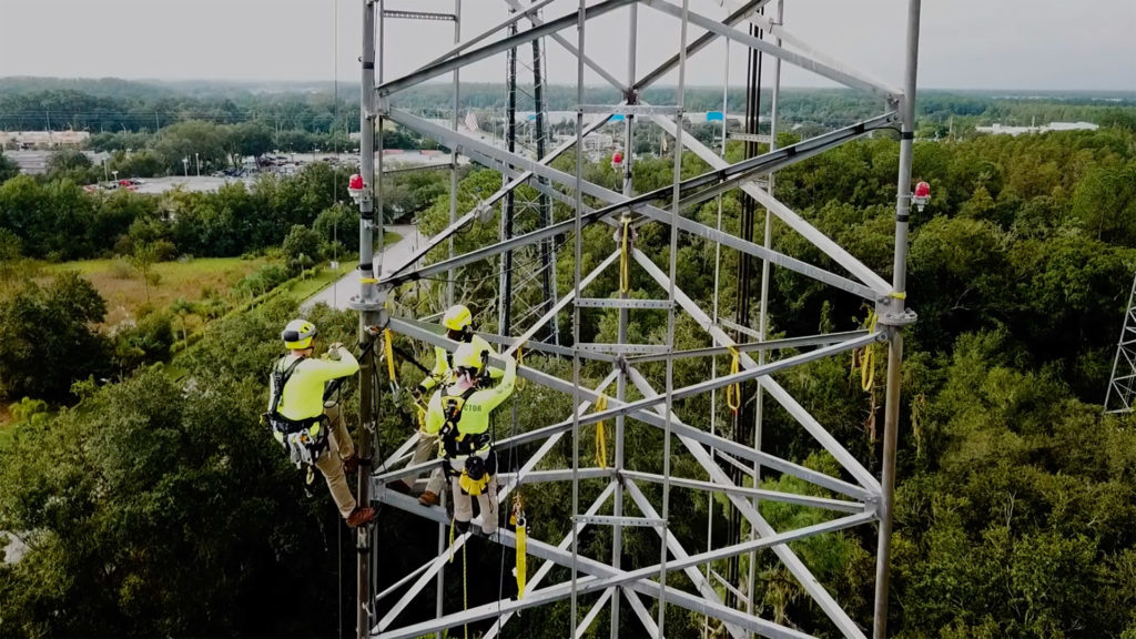 utility workers climbing cell tower