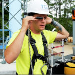 5g cell tower utility worker in a harness, hard hat and realwear display