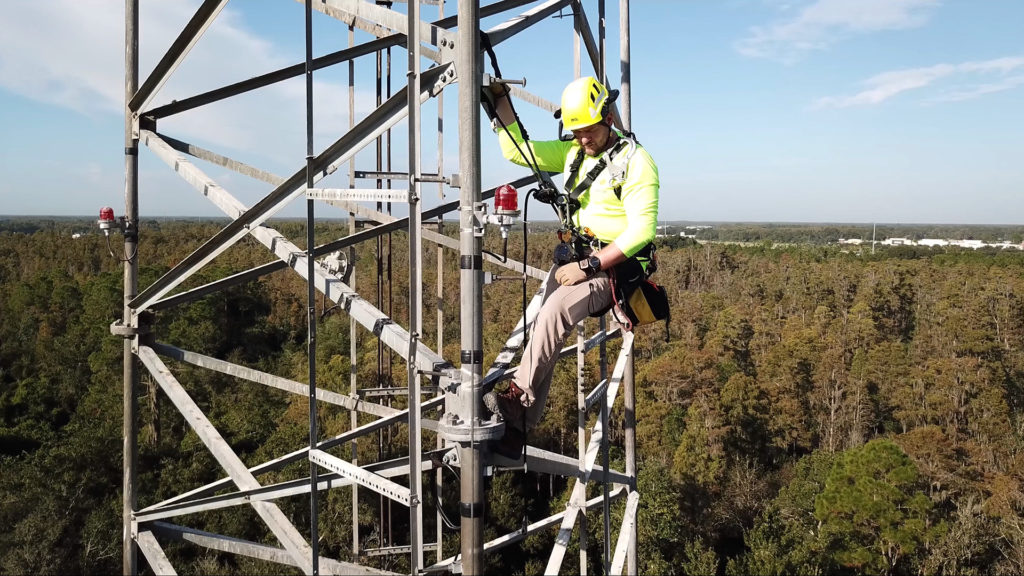 utility worker on cell tower in harness and wearing ar headset
