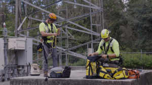 utility workers at the base of a cell tower