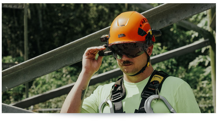 man in orange hard hat wearing harness and augmented reality headset