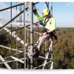 utility worker in a harness on a cell tower
