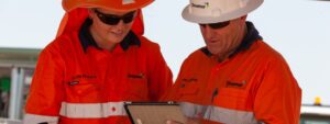 downer employees in orange jackets looking at a tablet